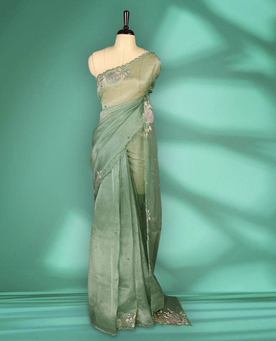 Pastel Green Colour organza saree featuring delicate floral embroidery with applique, bead, mirror, and thread detailing on the body and scalloped border, lending a soft feminine charm, paired with a matching blouse.
