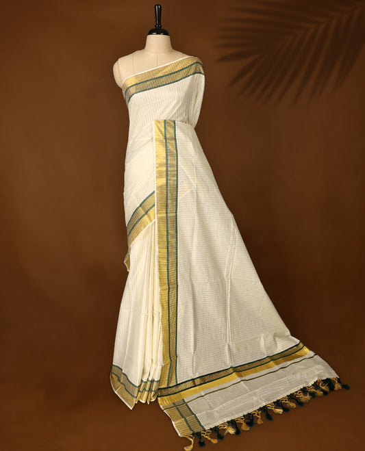 Elegant off white colour checked cotton Kerala saree with golden and green zari border, finished with tasselled pallu & Comes with a matching blouse, perfect for festive and traditional occasions.