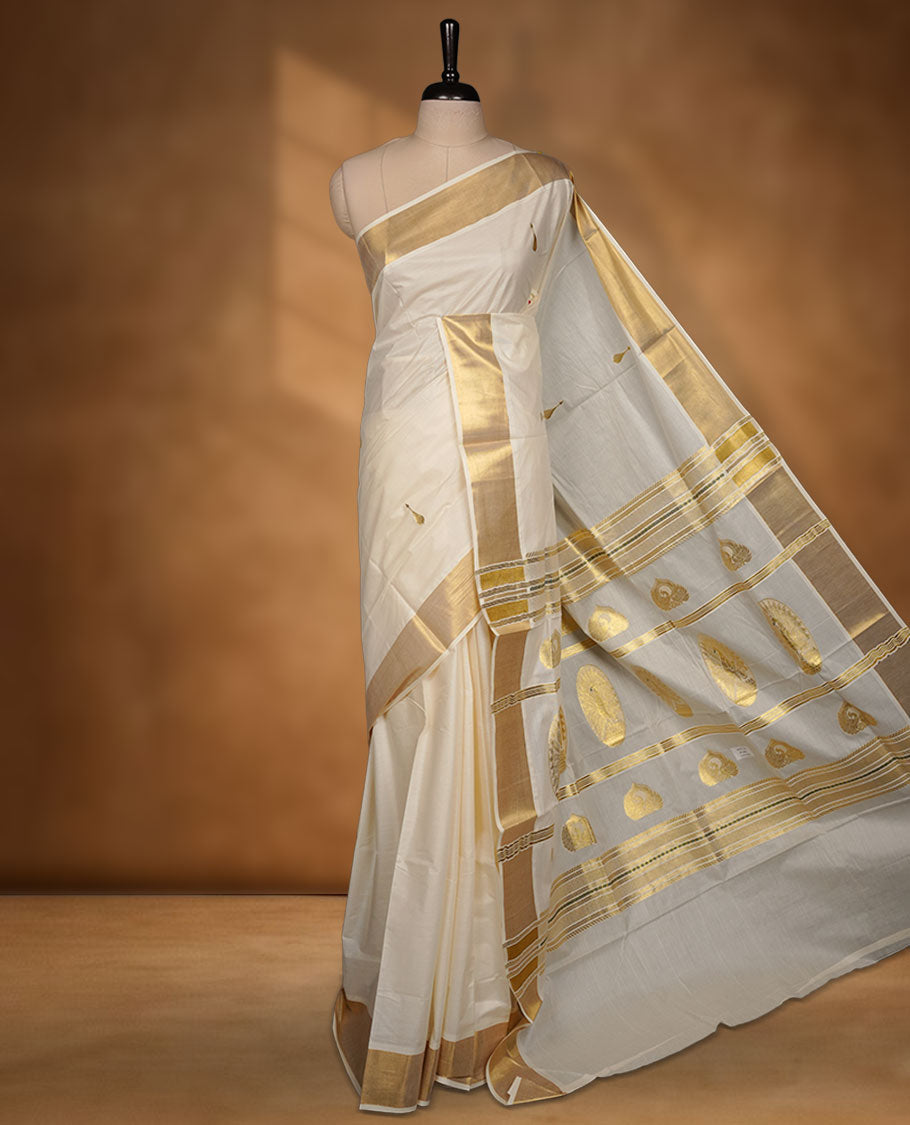 Off-white cotton Kerala saree featuring gold zari buttas, a broad kasavu border, and a traditional pallu, paired with a matching blouse.