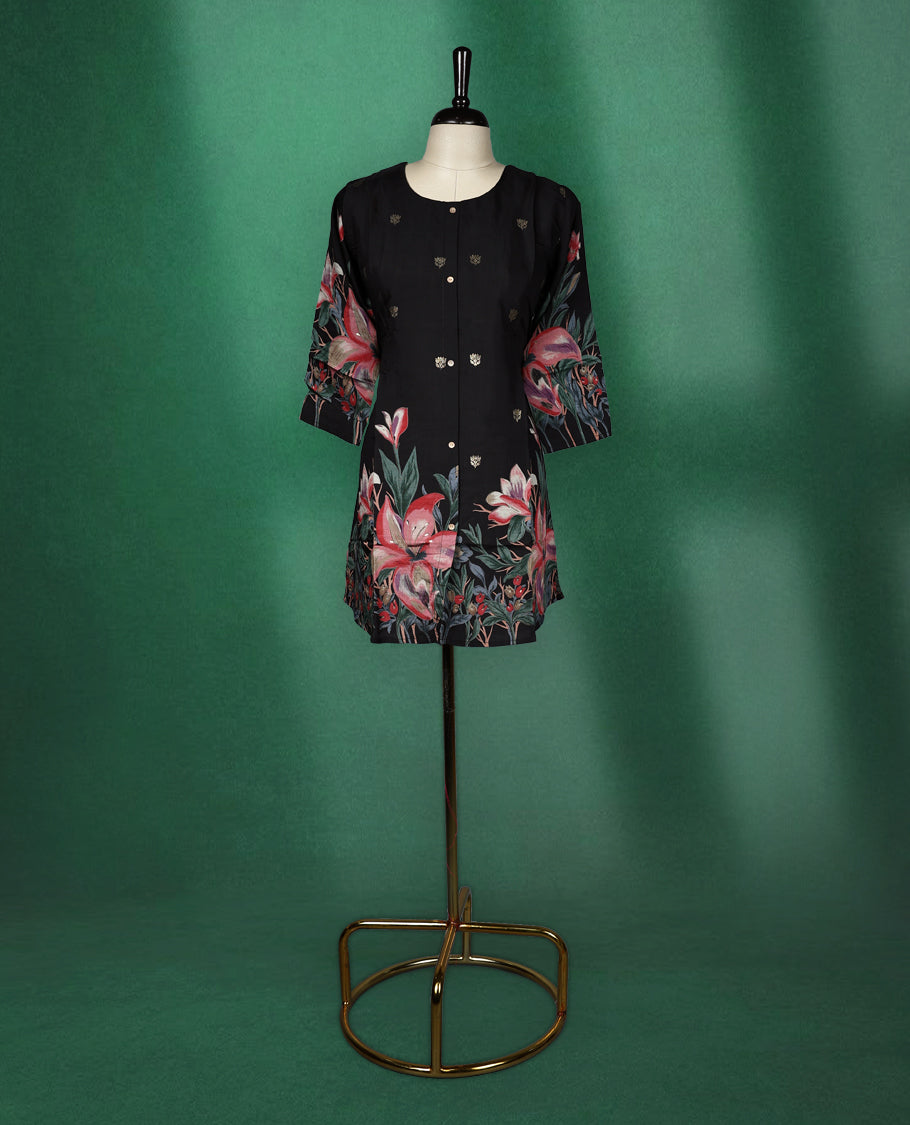 Black colour short kurti featuring a round neck and three quarter sleeves, adorned with soft golden motifs and a vibrant floral print along the hem and sleeves for a bold, elegant finish.