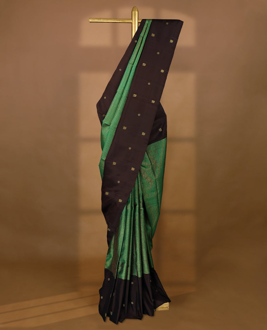 Green Colour pure traditional Kancheepuram silk saree featuring antique zari checks on the body, beautifully complemented by a dark chocolate simple border with delicate Chakkram and peacock motifs, and paired with a matching blouse.