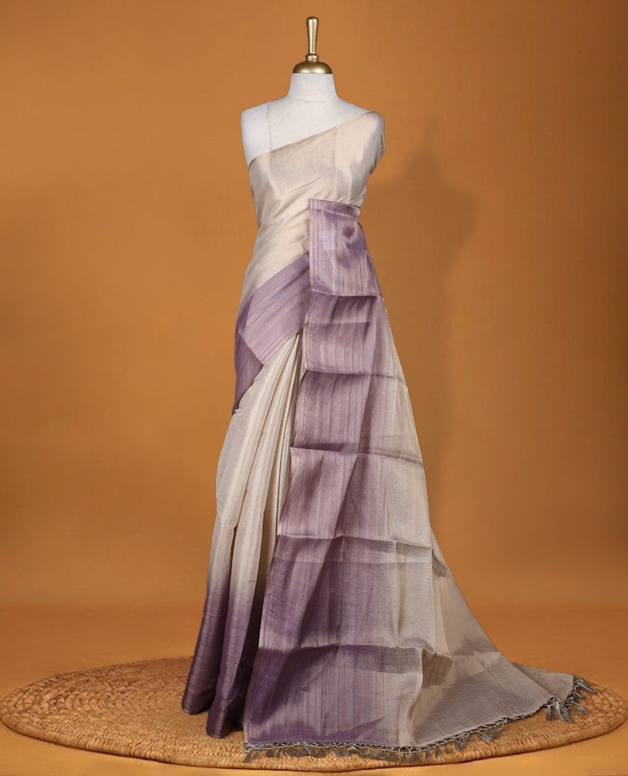 Beige and Lavender colour saree featuring a subtle woven texture & The shaded lavender pallu adds a graceful charm & Finished with delicate tassels and paired with a matching blouse piece.