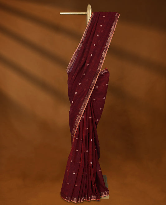 Maroon colour soft khadi cotton saree with small Beige Zari Flower motifs on the body, detailed woven Gold zari border, paired pallu with tussles, with matching blouse.