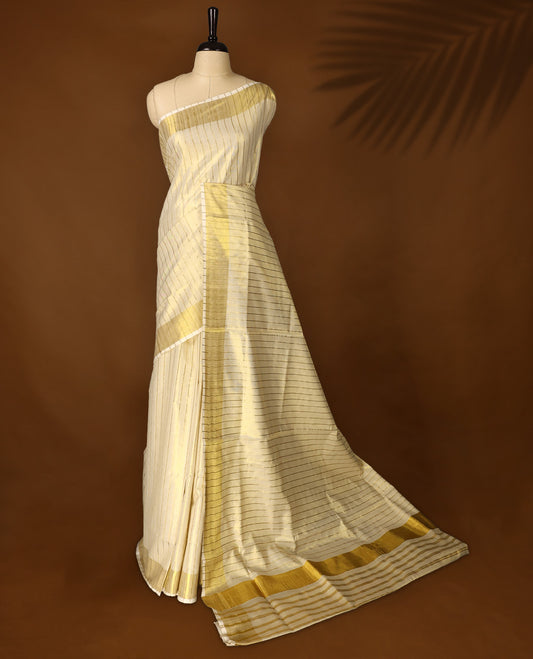Elegant off white colour tissue Kerala saree with golden zari stripes and broad borders, Lightweight with a subtle sheen, it includes a matching blouse & perfect for weddings, rituals, and festive occasions.