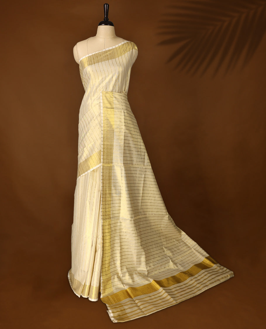 Elegant off white colour tissue Kerala saree with golden zari stripes and broad borders, Lightweight with a subtle sheen, it includes a matching blouse & perfect for weddings, rituals, and festive occasions.