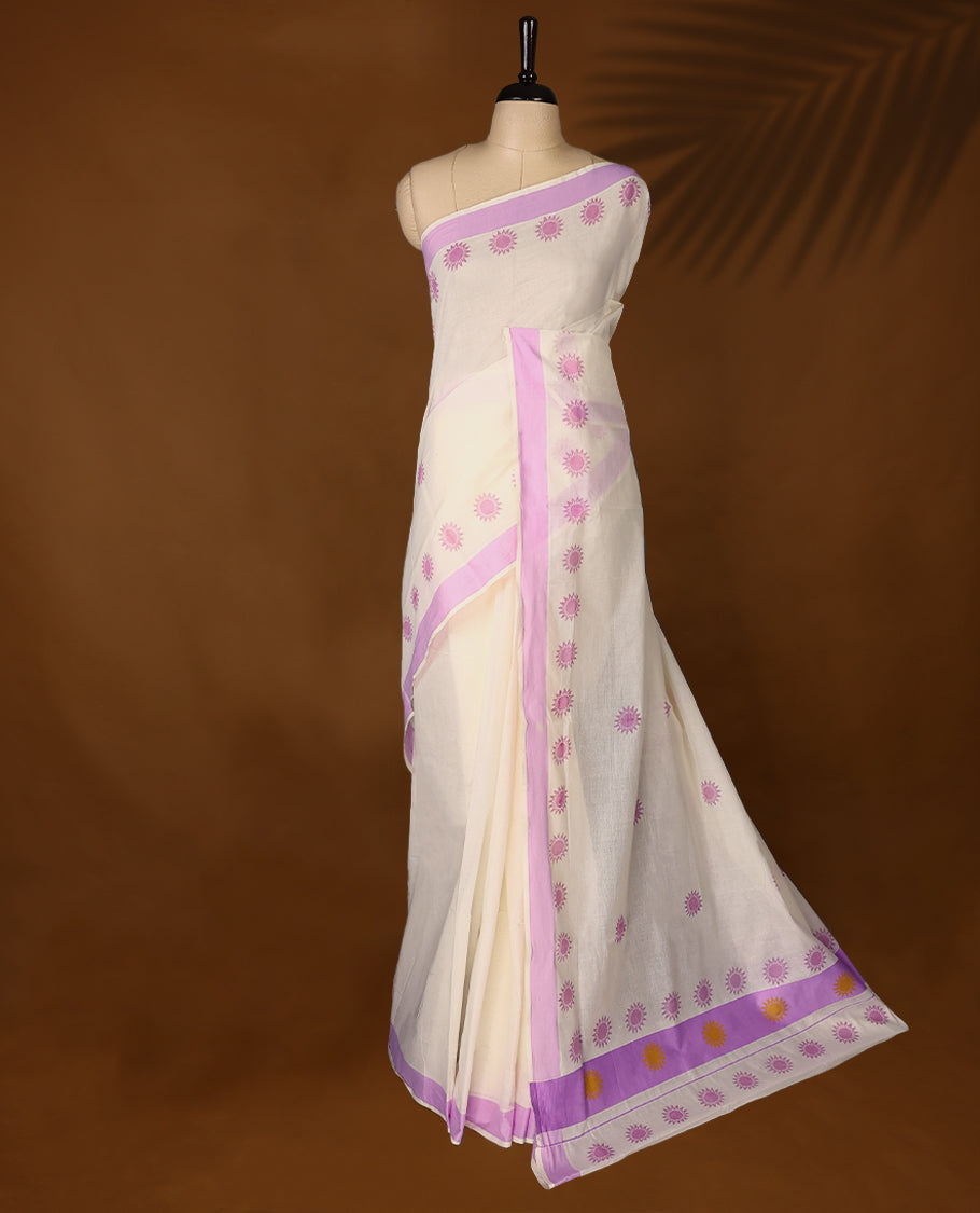 Elegant off white colour cotton Kerala saree featuring Plain body, Lavender colour border with Flower Block prints, Paired with matching blouse offering a classic and graceful look