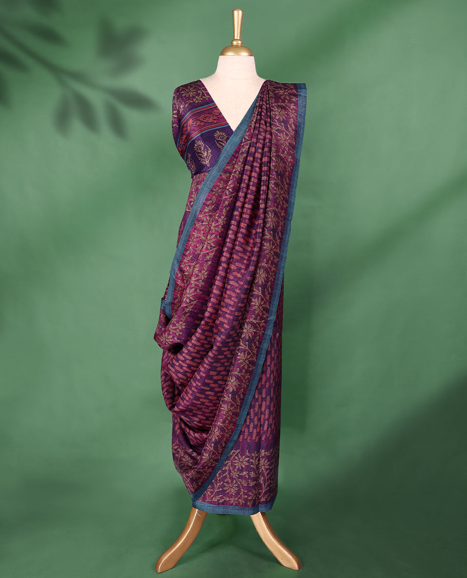 Plum purple colour Manipuri saree features a body with brick-red abstract motifs, highlighted by a contrasting indigo border and floral-printed pallu, and comes with a matching blouse.