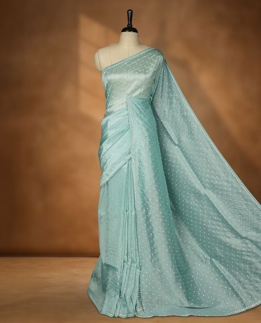 Pastel teal colour net shimmer fancy saree adorned with scattered white stone buttas all over the body, paired with a delicate stone worked border and matching blouse.