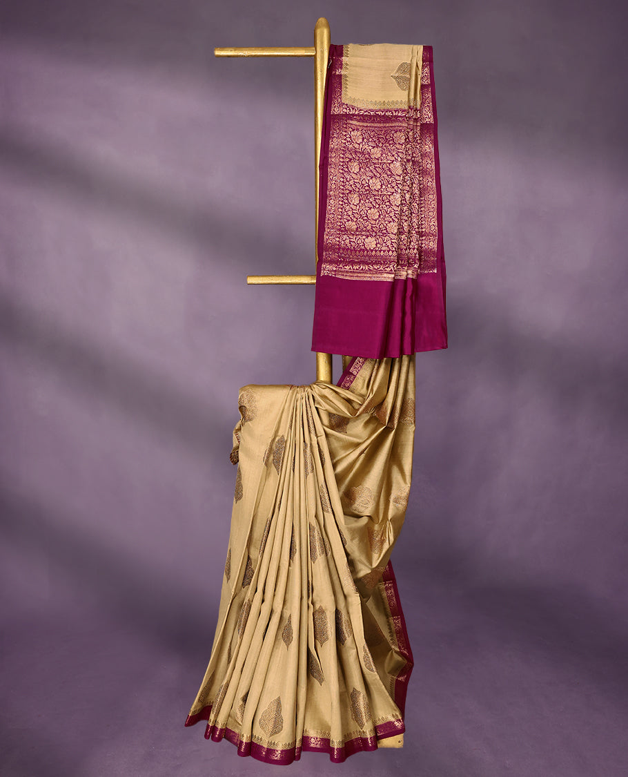 Beige Colour Pure Banaras Soft Silk Saree adorned with traditional antique zari motifs, paired with a hand dyed Dark Magenta antique style border and a matching blouse.