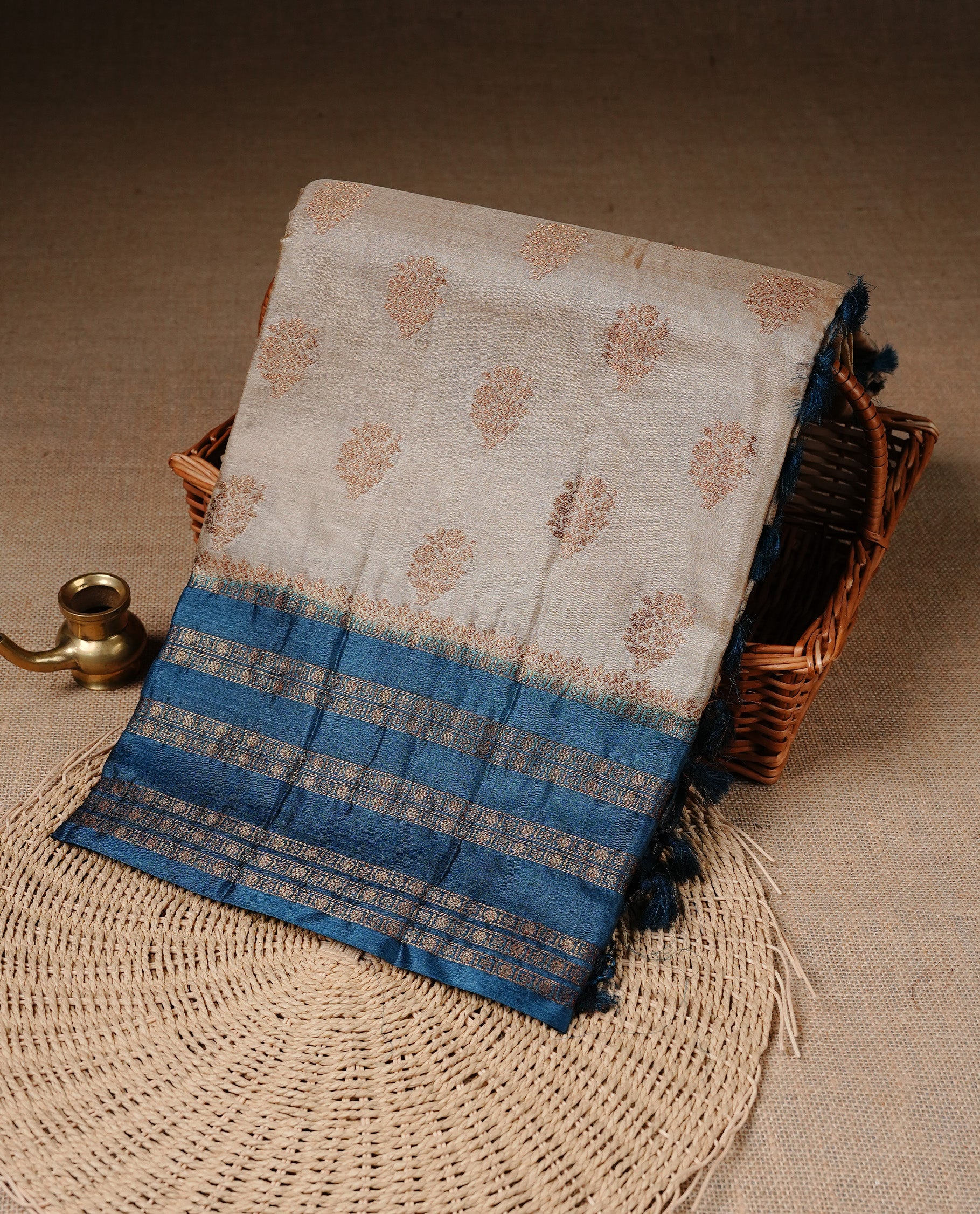 Golden Cream Colour Banaras tussar silk saree featuring Antique zari Motifs on body, Complemented by Blue colour variant with zari border, paired with matching blouse Piece.