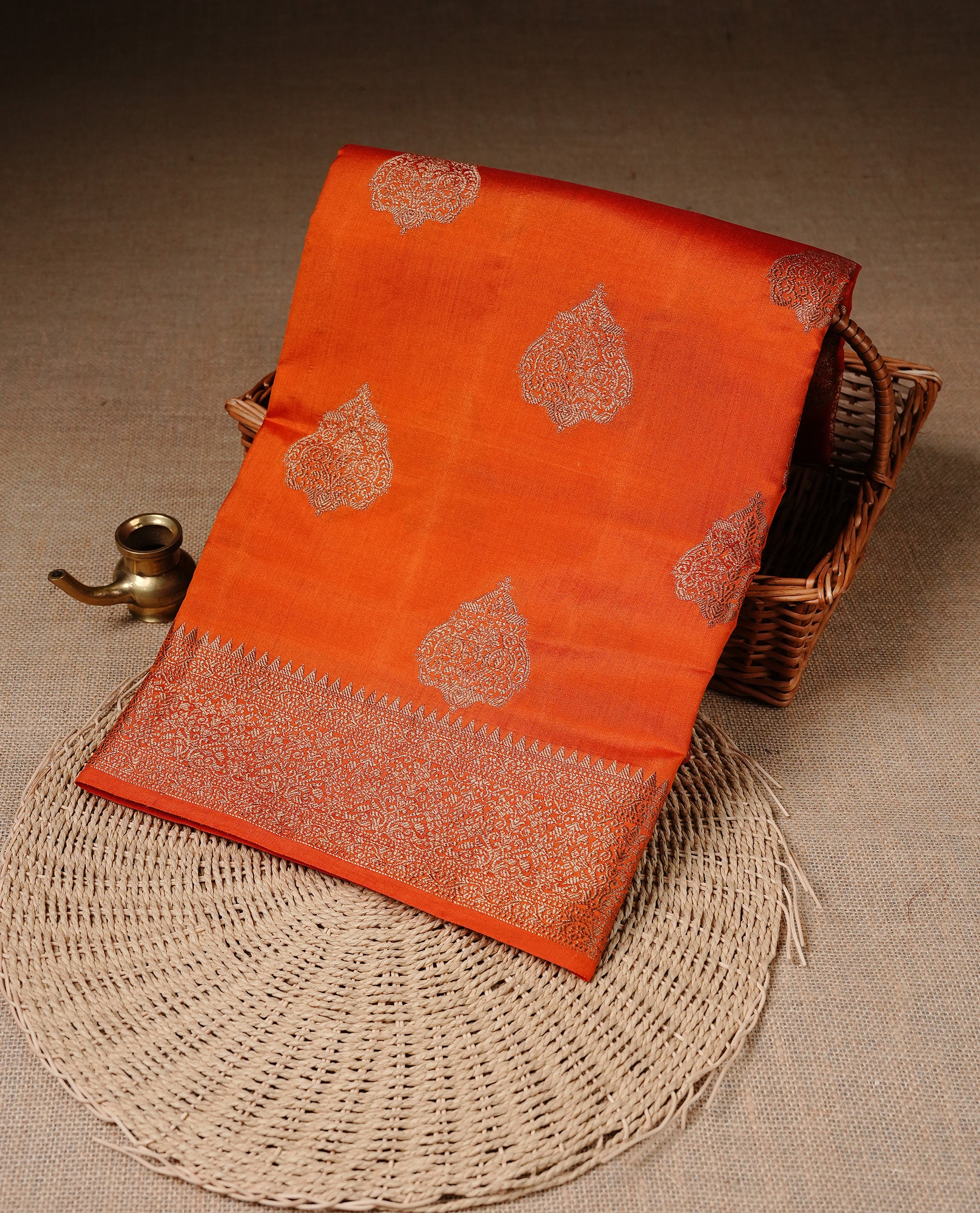 Orange Colour Pure Banaras Soft Silk saree featuring Antique Zari buttas in body, complemented by zari work on self colour border, paired with matching Blouse Piece.