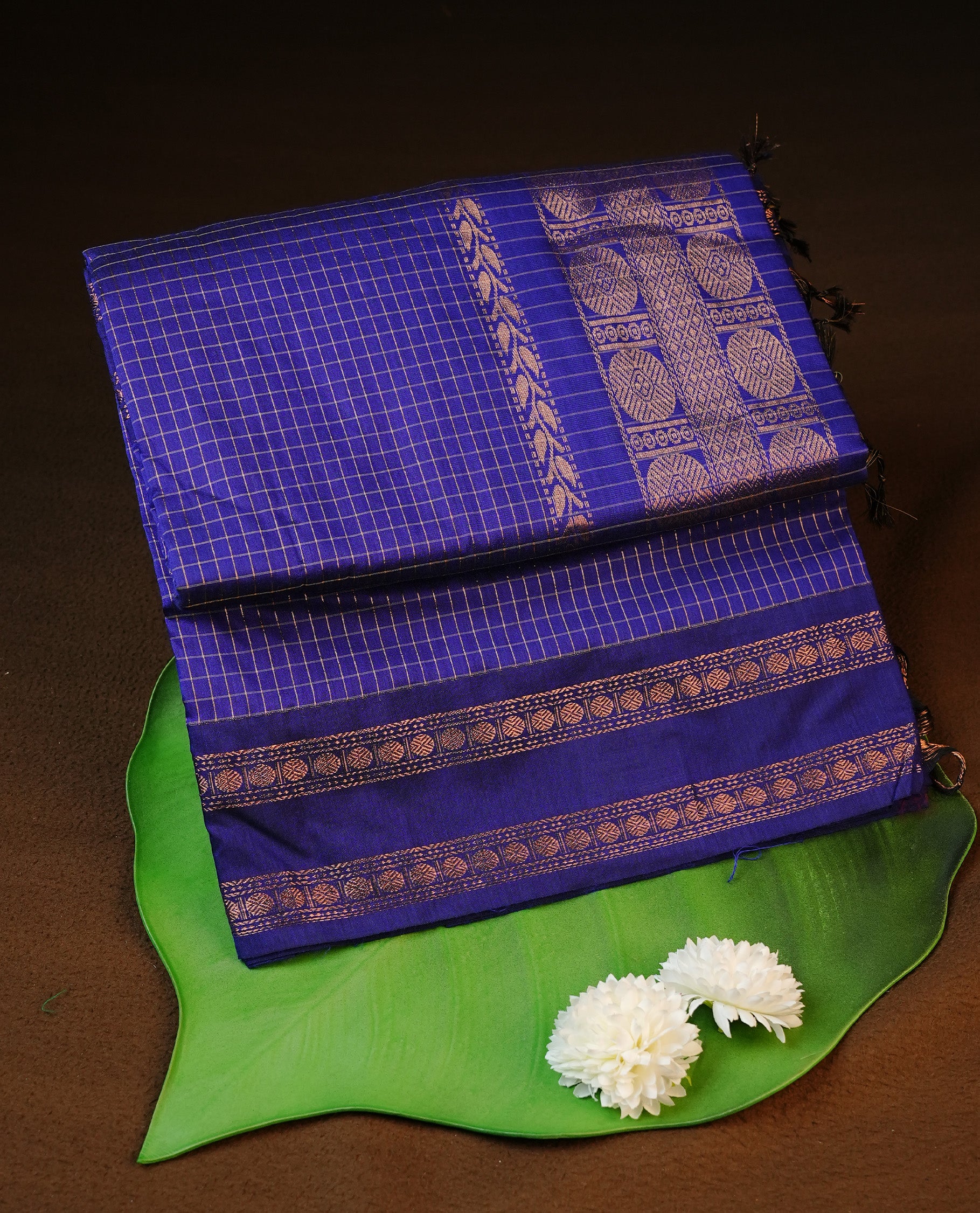 Navy blue colour kalyani cotton saree featuring gold zari strip pattern on body, complemented by self colour with Antique zari border, paired with matching blouse piece.