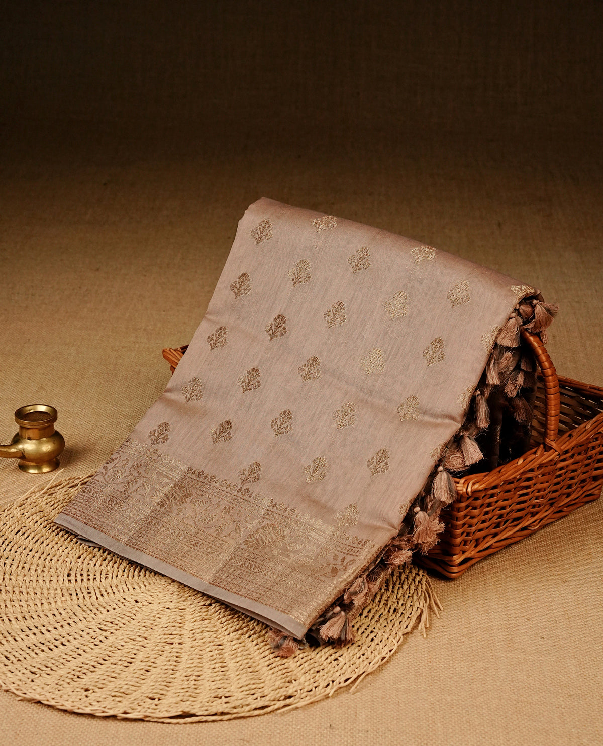 Beige colour Banaras silk saree featuring gold zari buttas on body, complemented by self colour with zari border, comes with matching blouse piece.