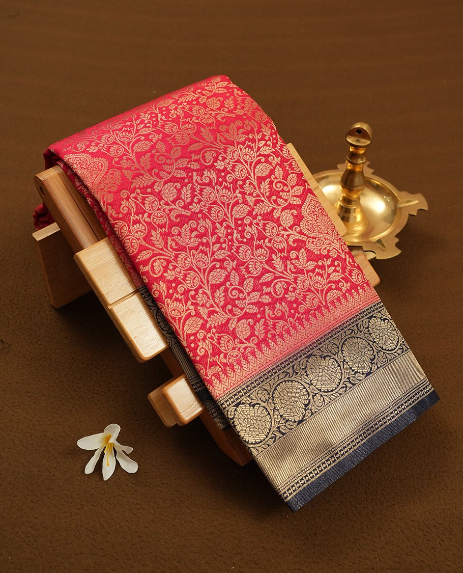 Red colour semi silk brocade saree featuring intricate Gold Floral kodi patterns across the body, complemented by a contrast navy blue colour woven border and pallu, paired with a matching blouse.