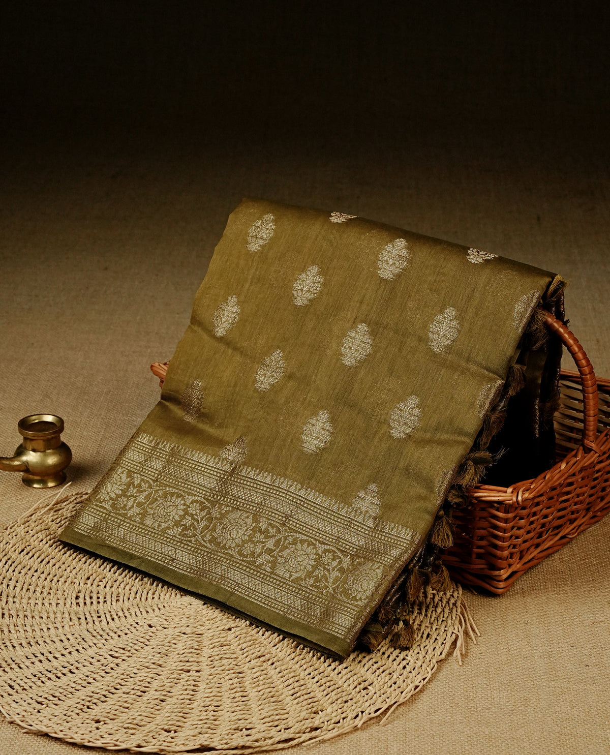 Olive colour Banaras silk saree featuring gold zari buttas on body, complemented by self colour with zari border, comes with matching blouse piece.