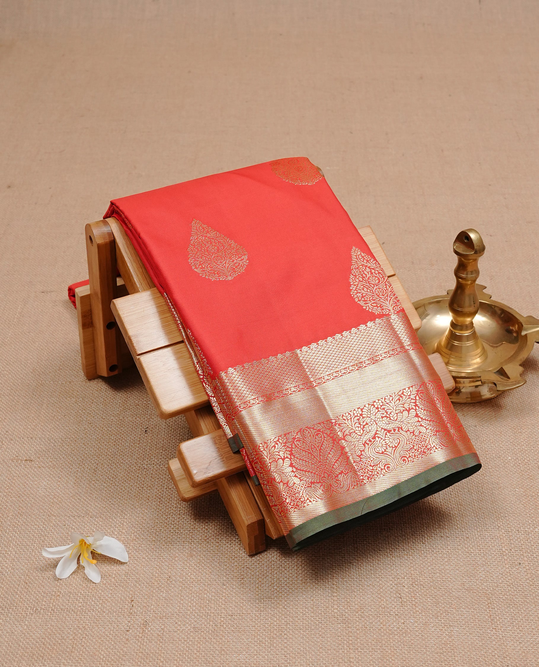 Red Colour semi wedding silk saree featuring Gold zari leaf motifs on body, complemented by Traditional zari on self colour border with green colour piping, paired with matching blouse piece.