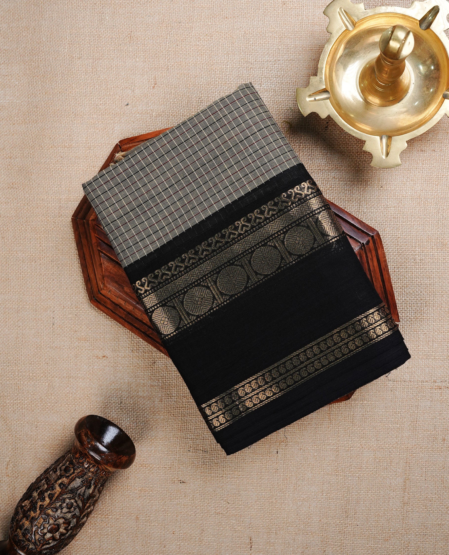 Grey colour chettinad cotton saree featuring Small check pattern on body, complemented by contrast black colour with gold zari border, paired with matching blouse piece.