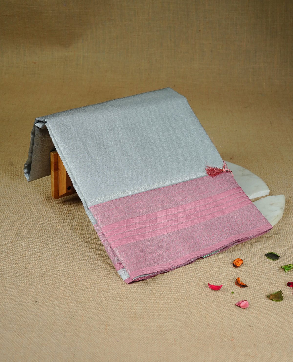 Grey colour semi silk saree featuring Silver zari Floral pattern on body, complemented by contrast Peach colour with silver zari border, comes with matching blouse piece.