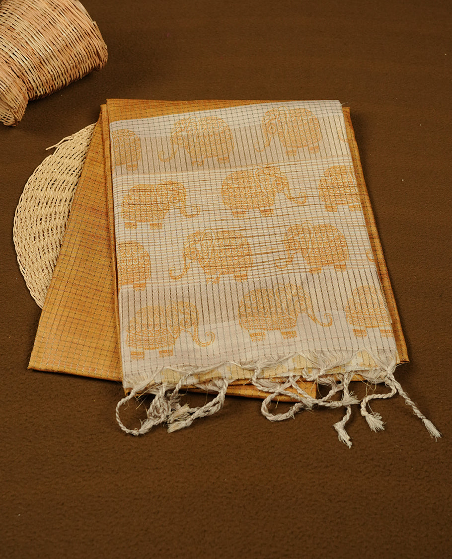 Golden yellow colour semi tussar silk saree featuring an all-over elephant motif print across the body, complemented by a contrasting pallu and border, and paired with a matching blouse piece.