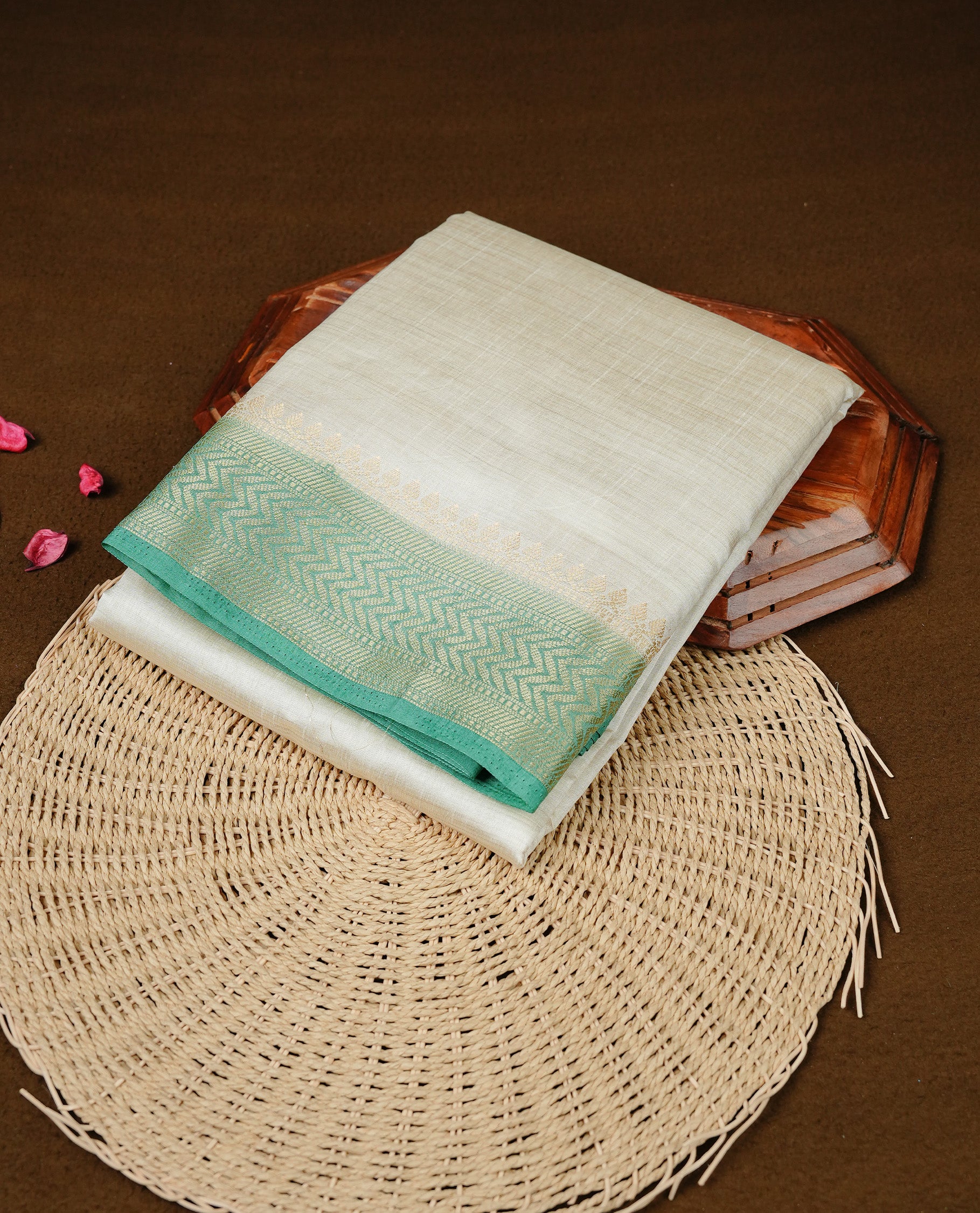 White cream colour Semi Tussar silk saree featuring an elegant plain body, accentuated by a contrast Aqua green border adorned with intricate gold zigzag zari work, paired with a matching blouse piece.