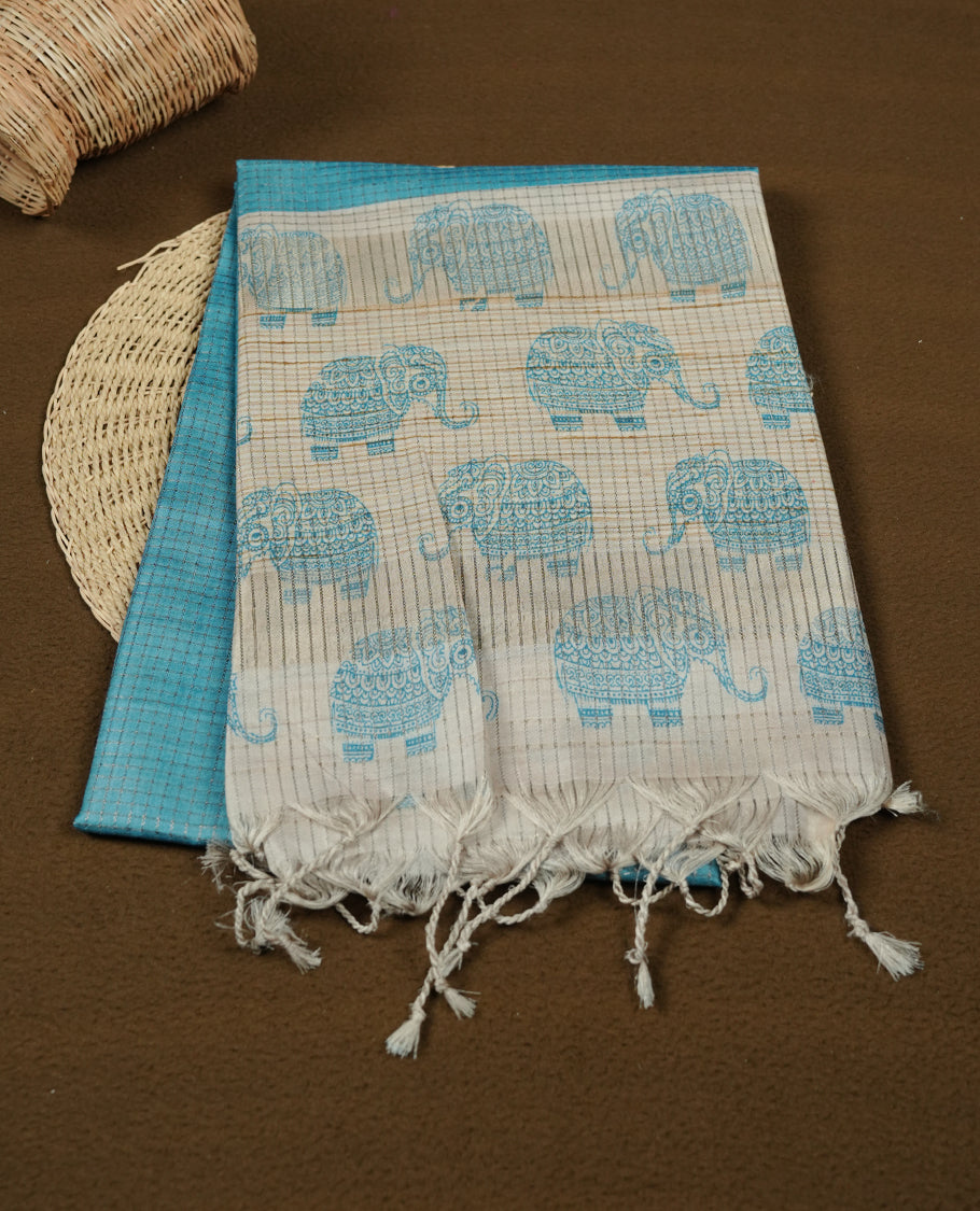 Sky-blue and off-white colour semi tussar silk saree featuring an all-over elephant motif print across the body, complemented by a contrasting blue pallu and border, and paired with a matching blouse piece.