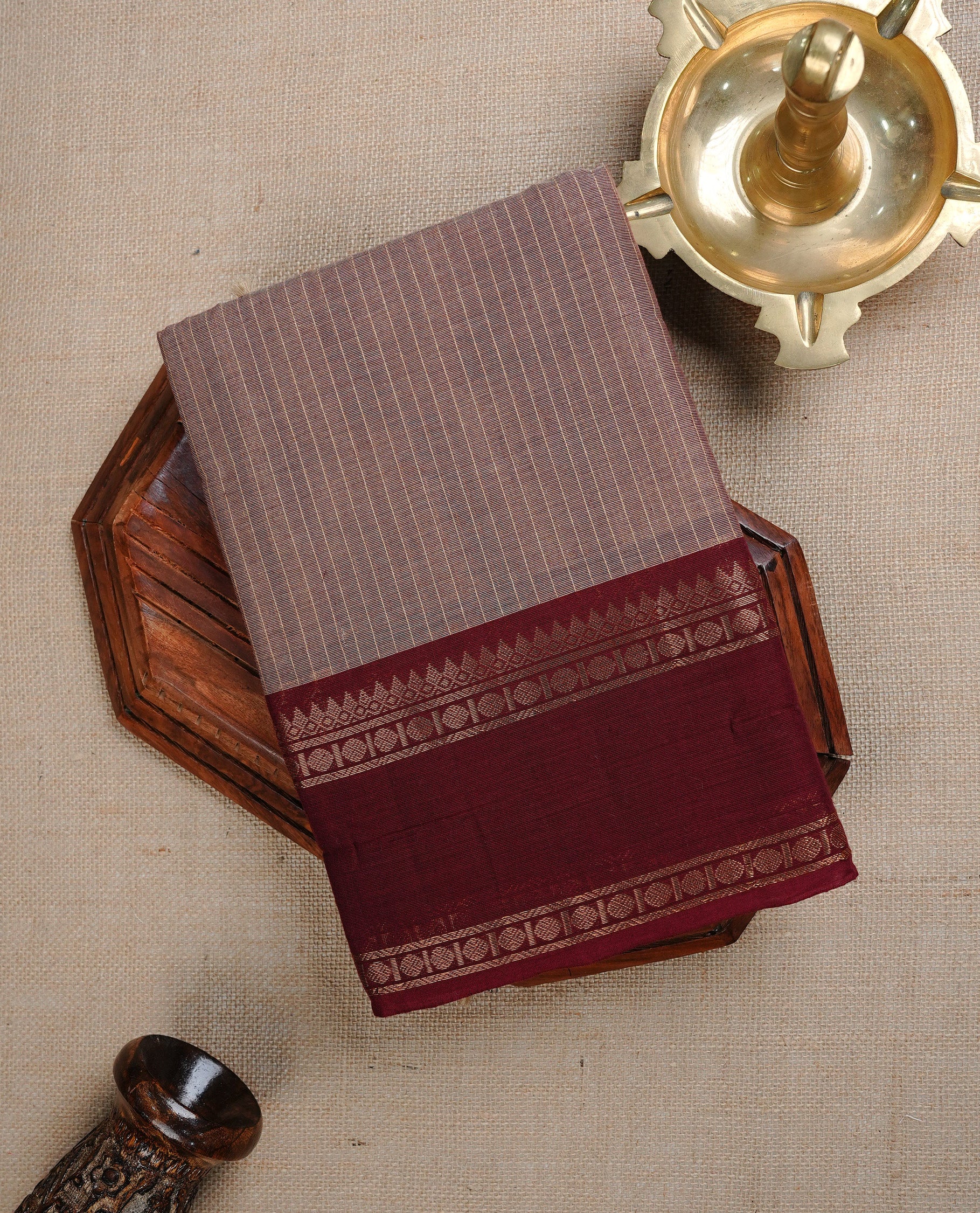 Brownish Grey colour chettinad cotton saree featuring Gold Stripes on body, complemented by Contrast Maroon Colour With Gold Zari border, paired with matching blouse piece.
