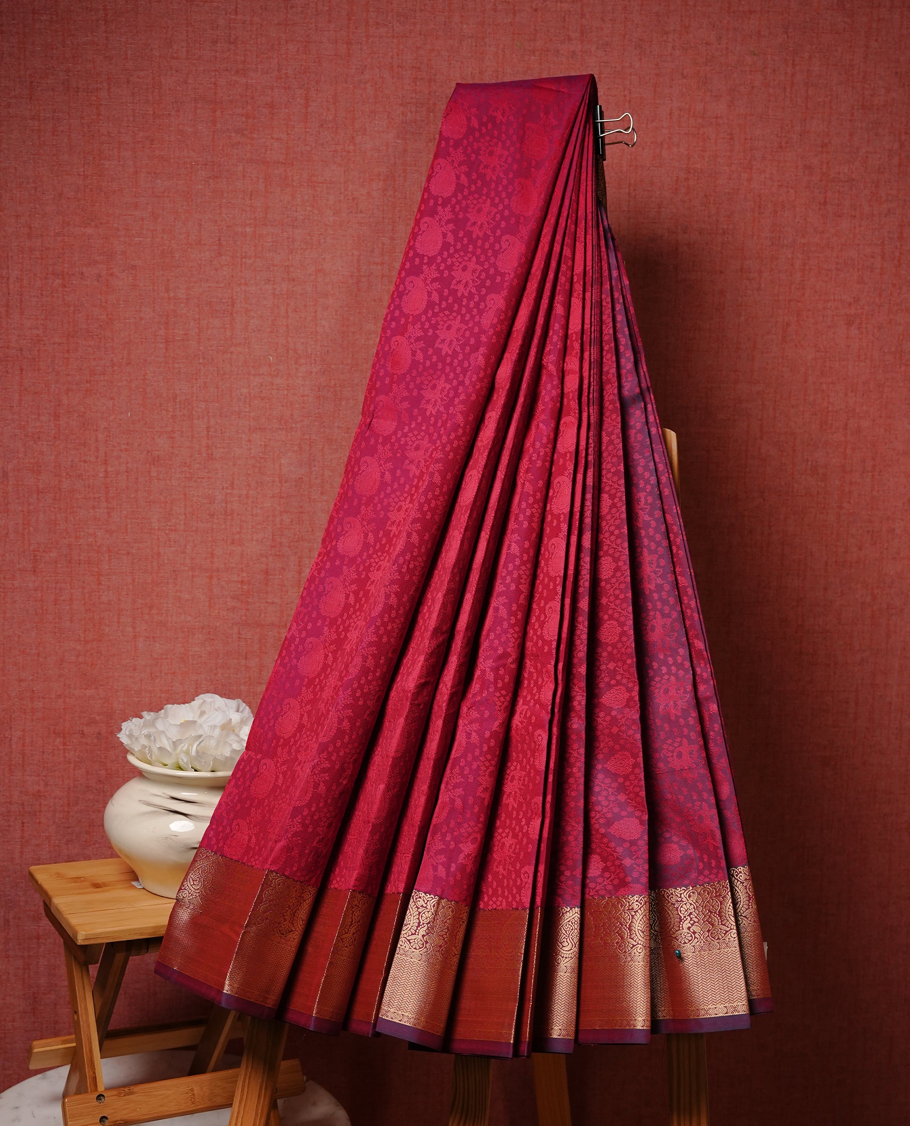 Reddish pink colour Semi silk saree Featuring Self zari Pattern on body, complemented by Maroon colour with gold zari border, paired with matching blouse piece.
