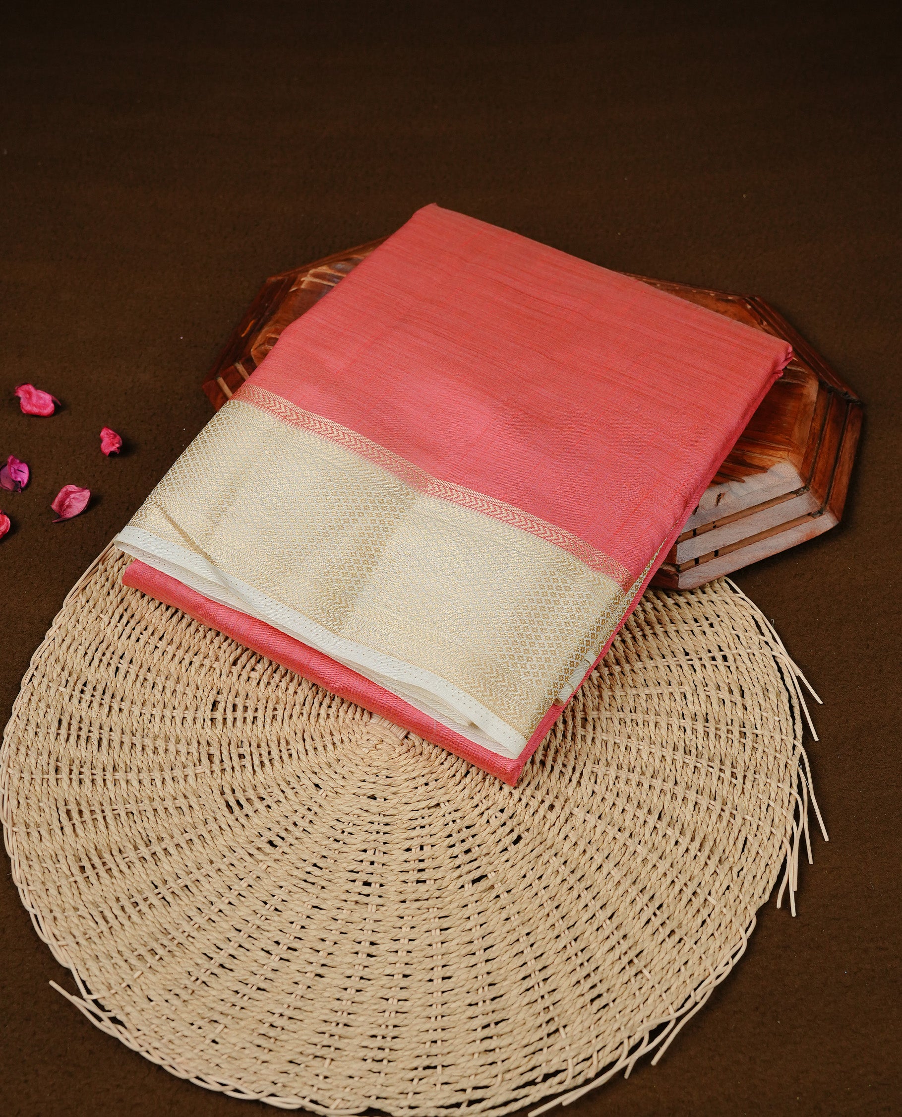 Pinkish peach colour Semi Tussar silk saree featuring an elegant plain body, accentuated by a contrast cream border adorned with intricate gold zari work, paired with a matching blouse piece.