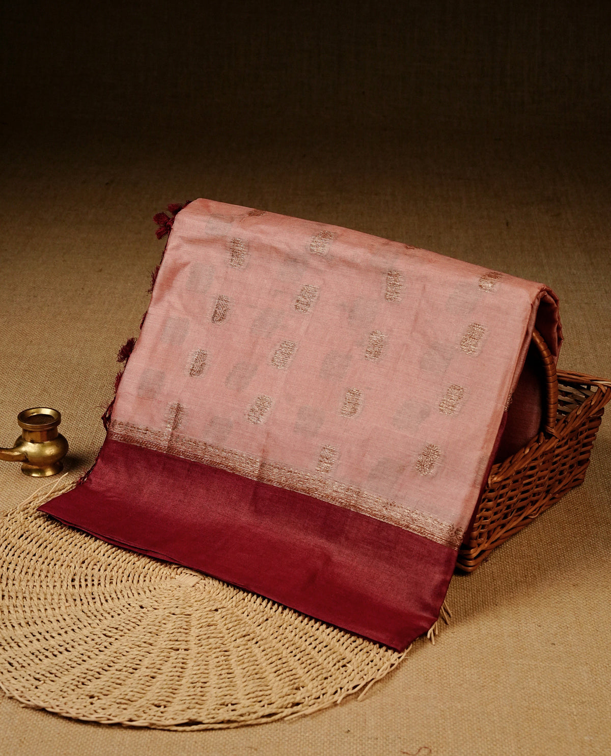 Light peach colour banaras silk saree featuring Gold zari buttas on body, complemented by contrast maroon colour border, comes with matching blouse piece.