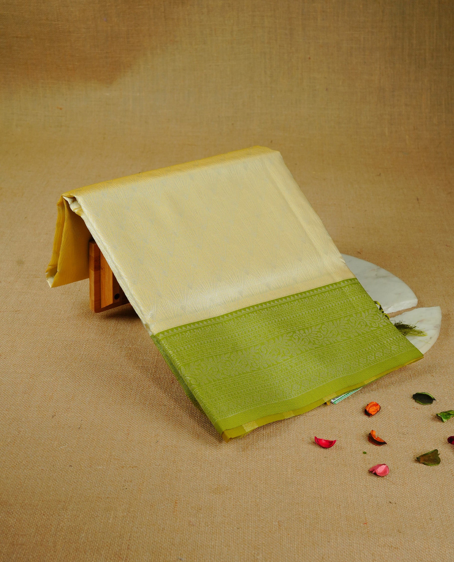 Pastel yellow colour semi silk saree featuring Silver zari pattern on body, complemented by contrast Green colour with silver zari border, comes with matching blouse piece.