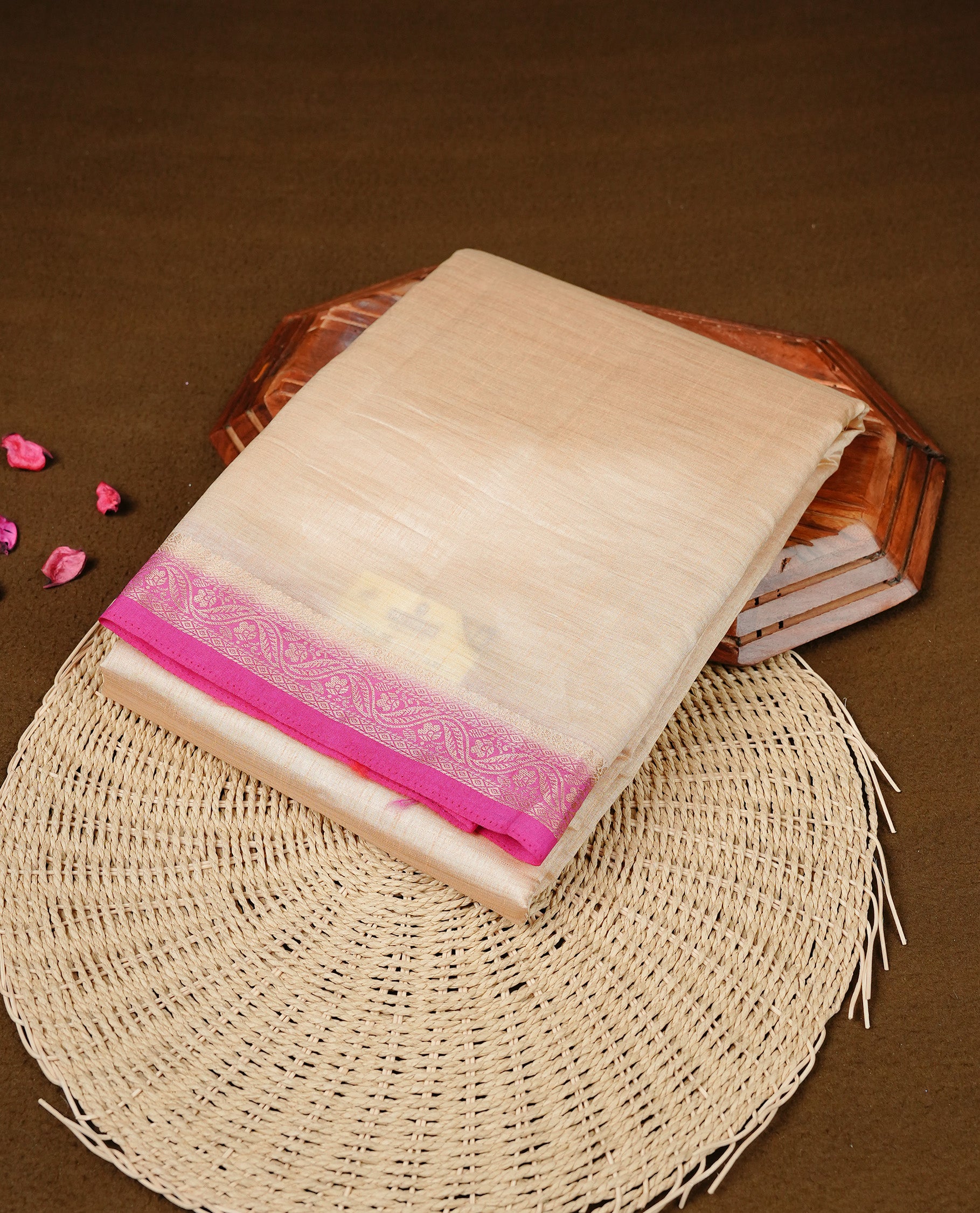 Cream colour Semi Tussar silk saree featuring an elegant plain body, accentuated by a contrast pink border adorned with intricate gold floral kodi zari work, paired with a matching blouse piece.