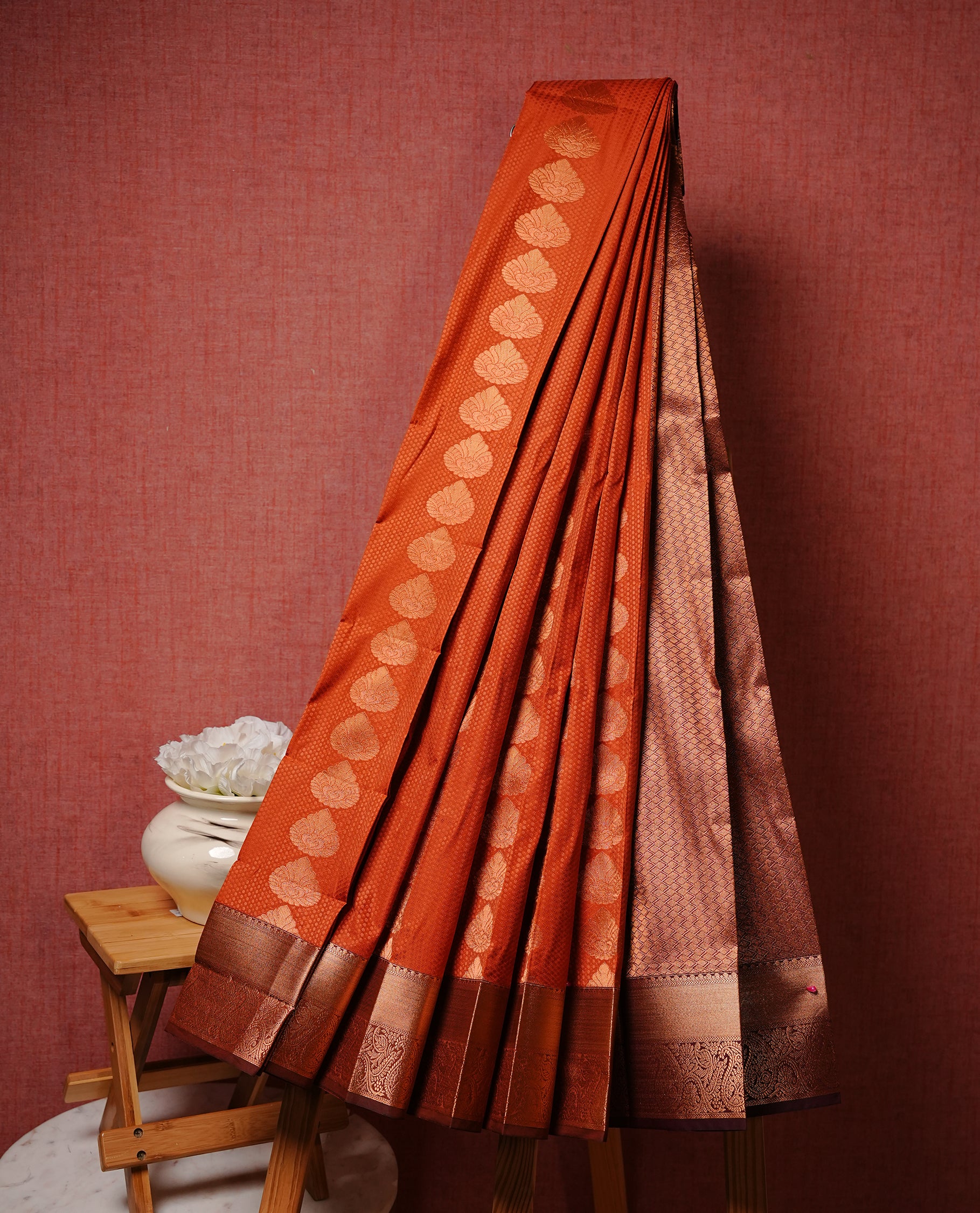 Rust orange colour Semi silk saree Featuring gold zari motifs on body, complemented by contrast brown colour with gold zari border, paired with matching blouse piece.