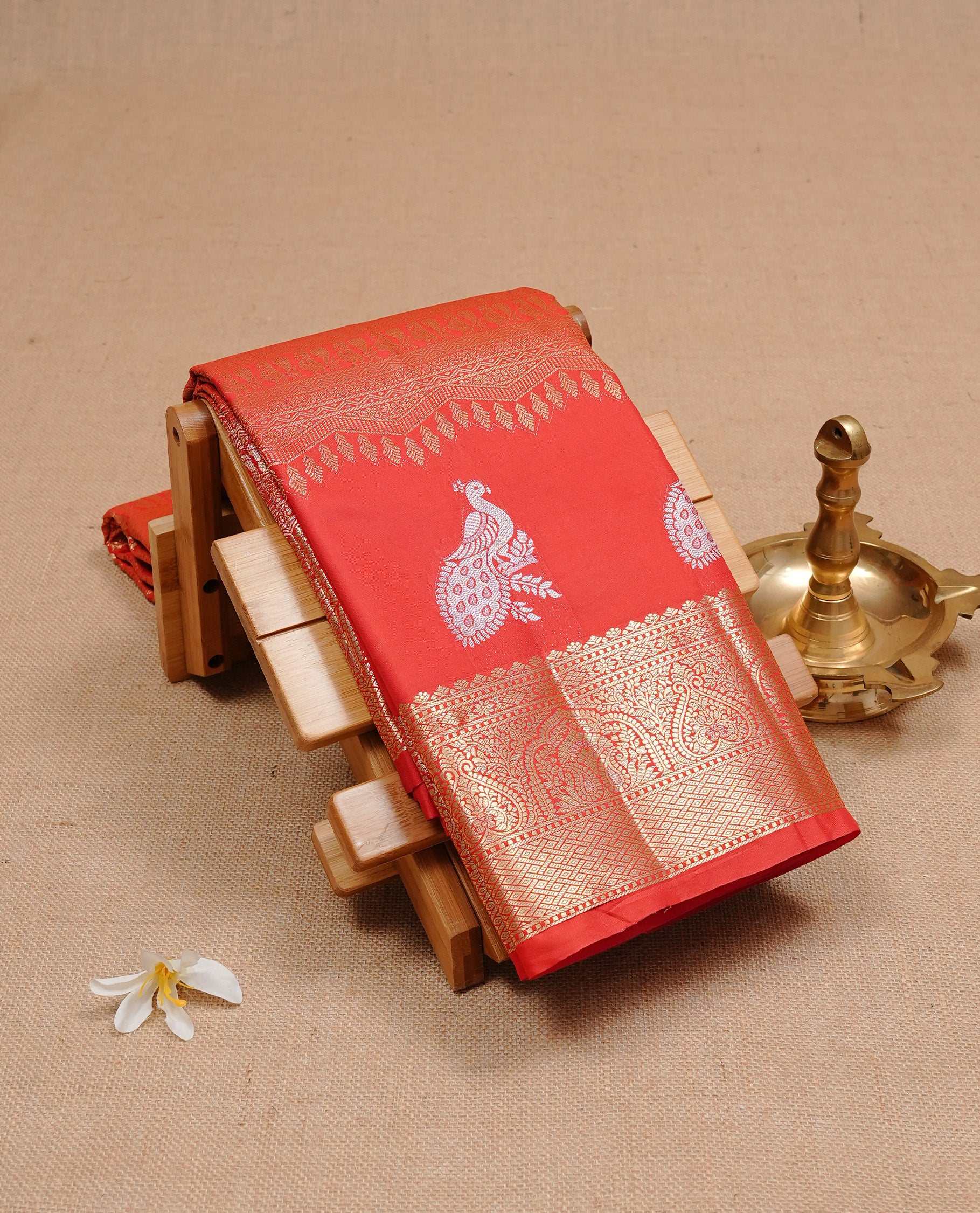 Red colour semi wedding silk saree featuring Gold zari pattern on body, complemented Silver Peacock motifs & gold zari border, paired with matching blouse piece.