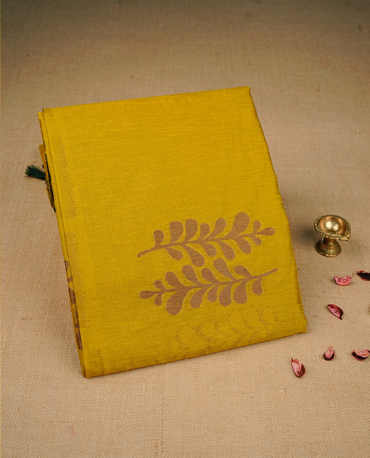 Mustard yellow colour semi linen saree with elegant gold zari Leaf motifs across the body, complemented by a contrast forest Green colour with grand gold zari pallu and a borderless design, paired with a matching blouse piece.