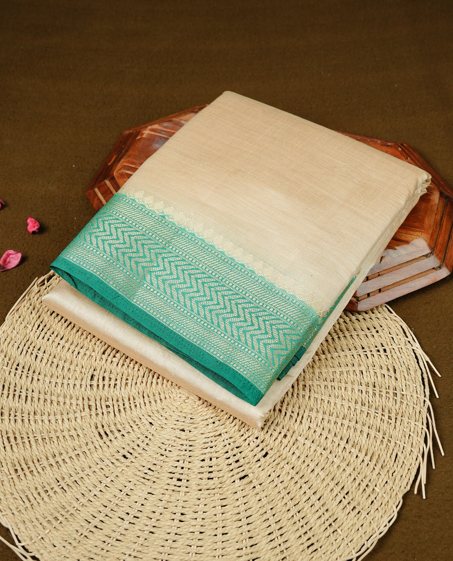 Cream colour Semi Tussar silk saree featuring an elegant plain body, accentuated by a contrast Green border adorned with intricate gold zigzag zari work, paired with a matching blouse piece.