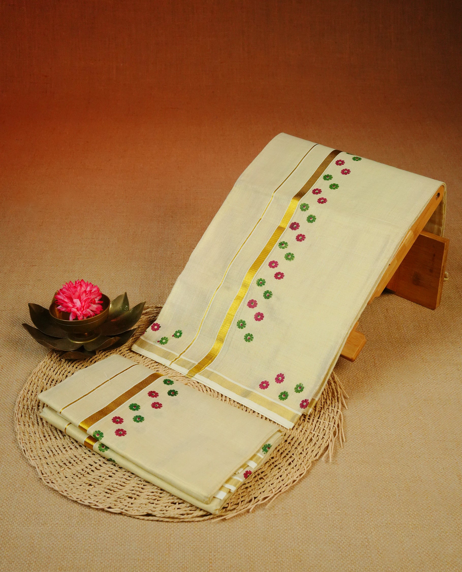 Cream Colour tissue set mundu featuring a plain body, enhanced with Green & Magenta Colour Floral prints with a gold zari kara.