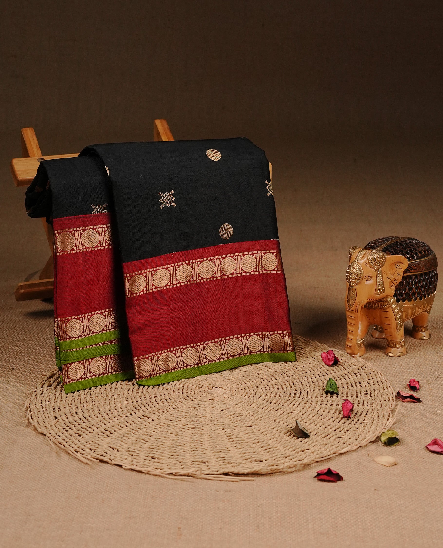 Black colour Traditional Kancheepuram silk saree featuring gold zari motifs on body, enhanced with contrast Red with traditional with green piping border, paired with matching blouse piece.