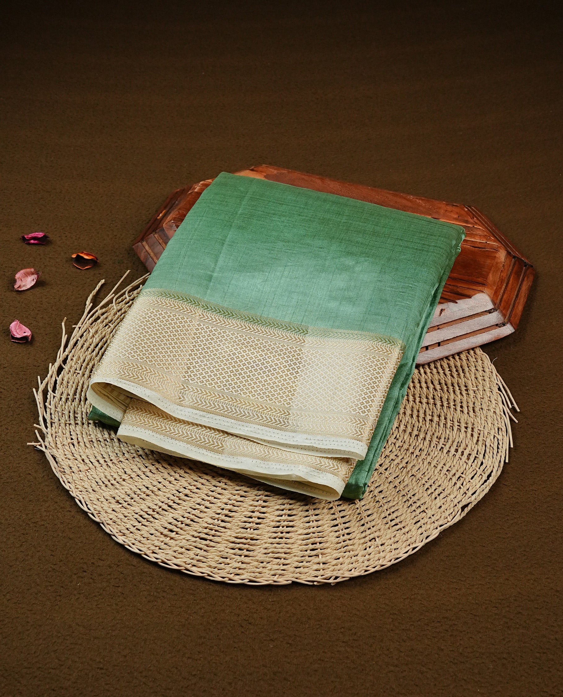 Green colour Semi Tussar silk saree featuring an elegant plain body, accentuated by a contrast cream border adorned with intricate gold zari work, paired with a matching blouse piece.