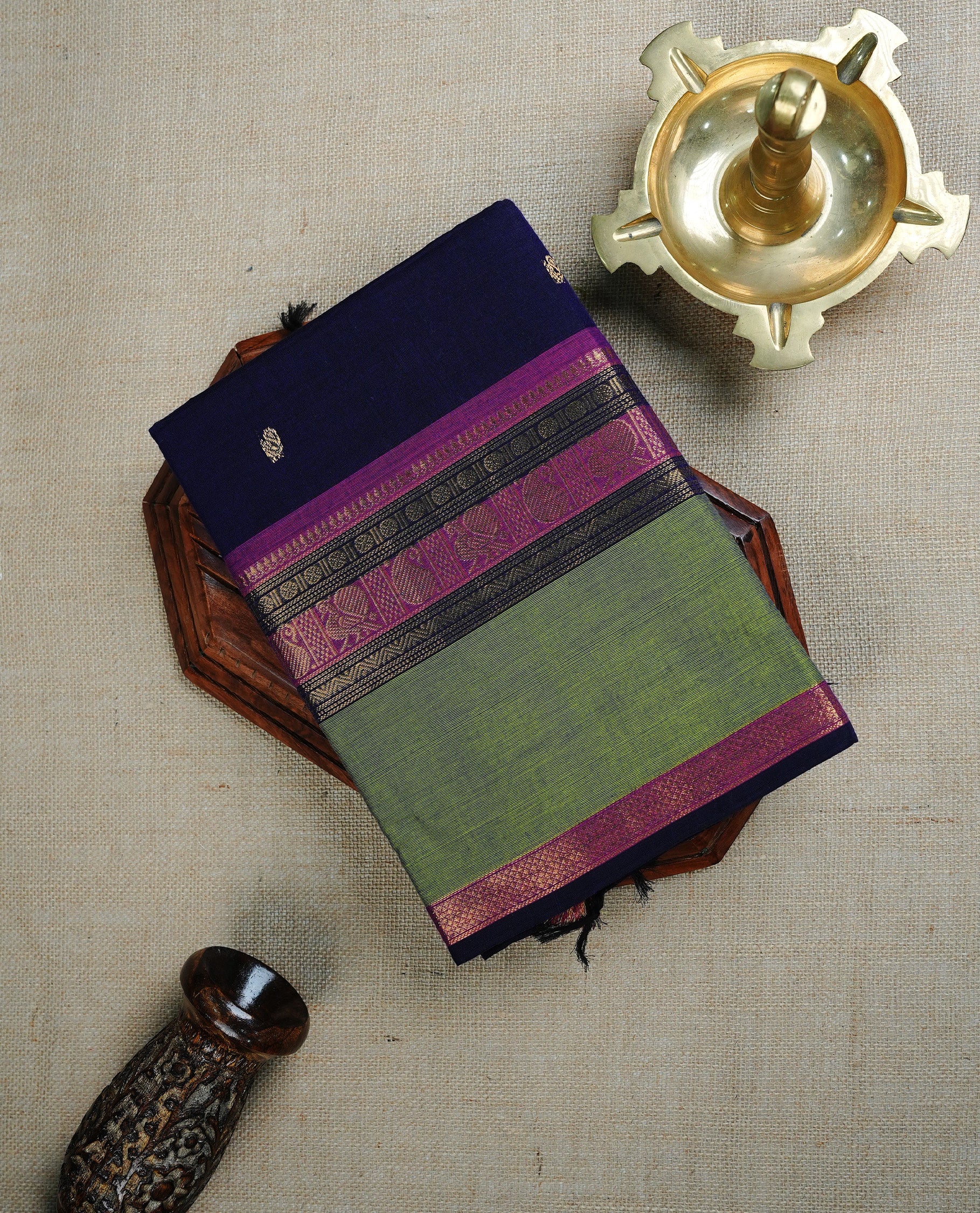 Navy Blue colour chettinad cotton saree featuring Gold Motifs on body, complemented by Contrast Green & Pink Colour With Gold Zari border, paired with matching blouse piece.