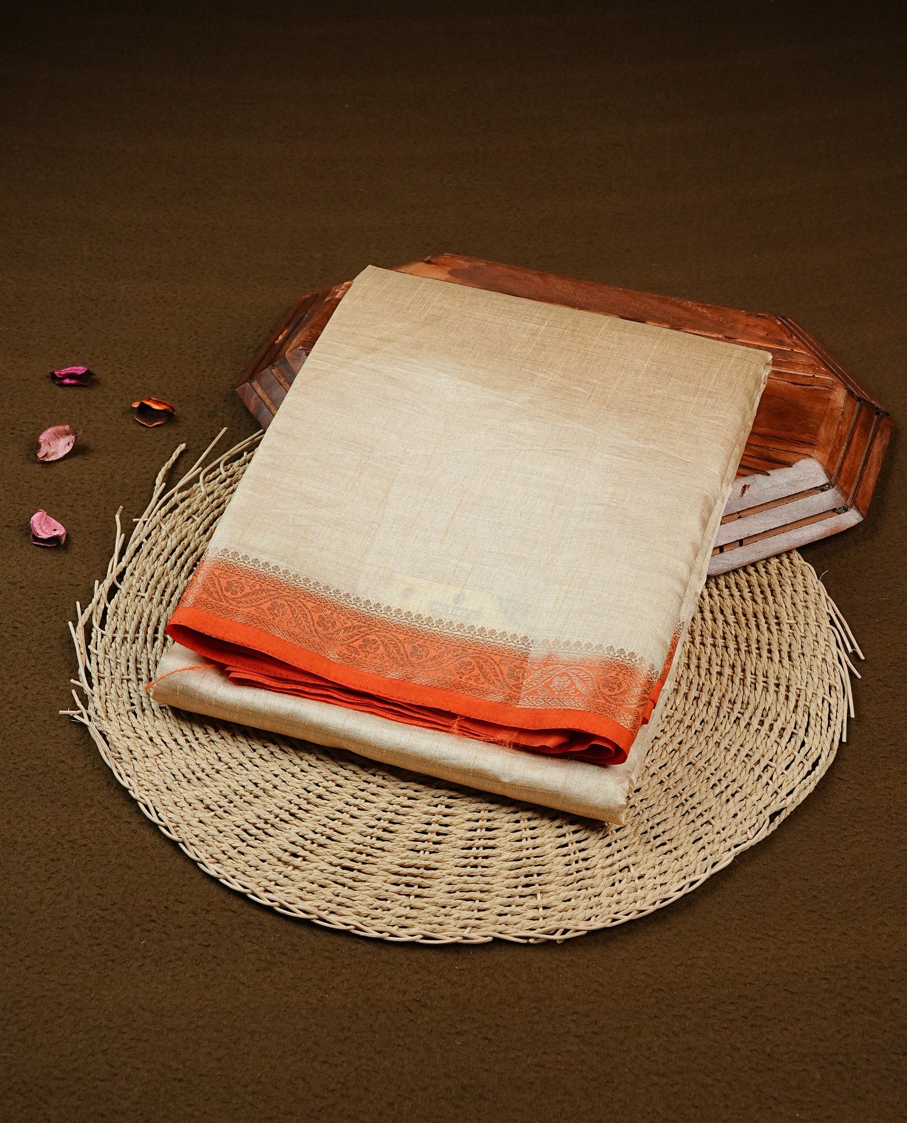 Cream colour Semi Tussar silk saree featuring an elegant plain body, accentuated by a contrast Orange border adorned with intricate gold Floral kodi zari work, paired with a matching blouse piece.