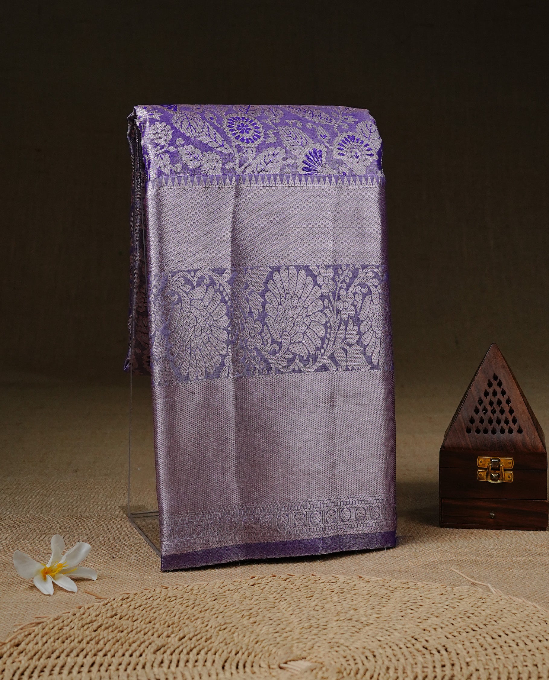 Light purple colour tissue saree featuring rose gold zari floral kodi pattern on the body, highlighted by a self colour border with rose gold traditional zari, paired with a matching blouse piece.