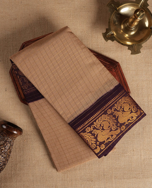 Beige colour Chettinad cotton saree adorned with subtle checked patterns on the body, complemented by an exquisite dark maroon border featuring golden peacock motifs & Paired with a matching blouse piece.