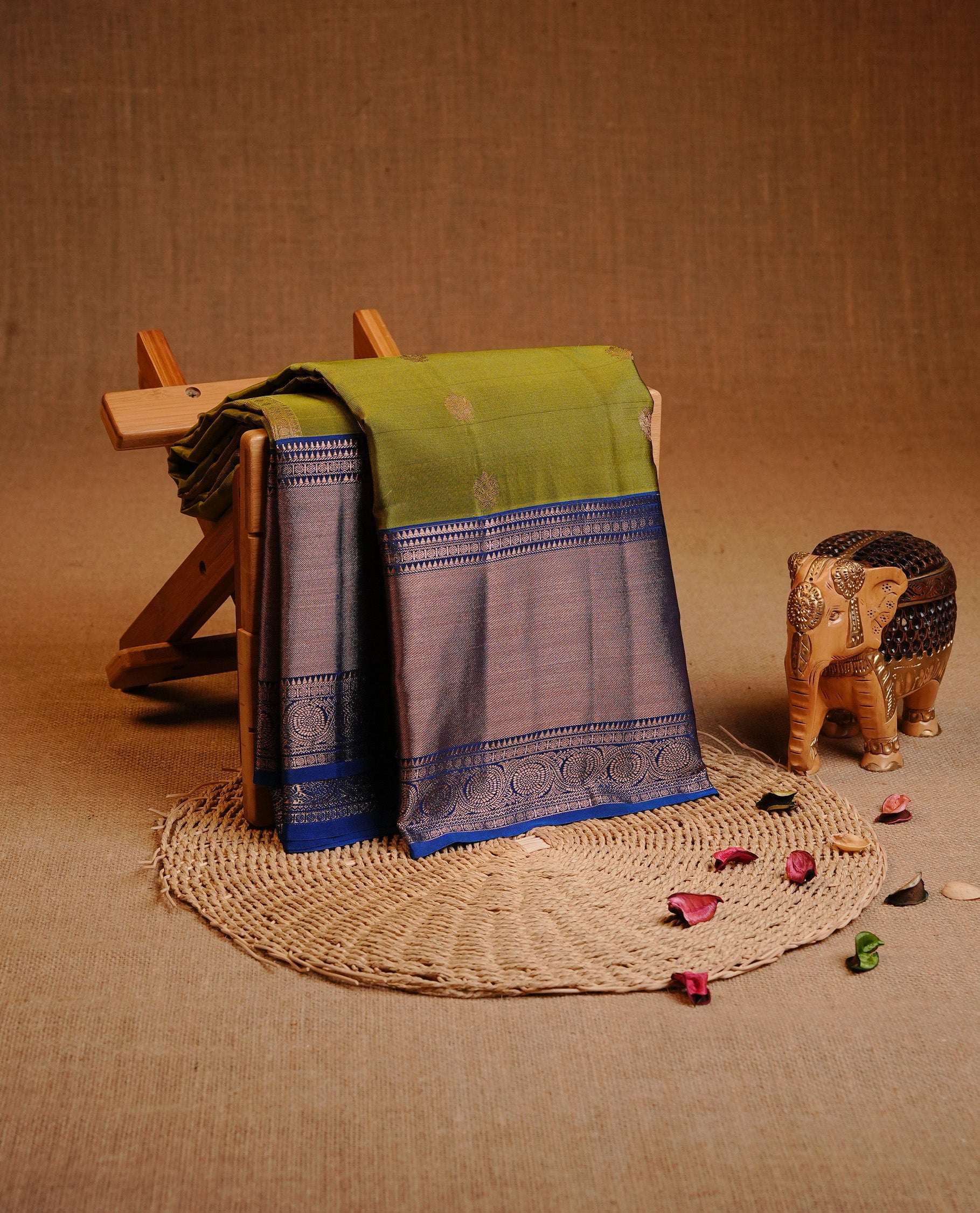 Olive Green Colour Traditional Kancheepuram Slik Saree Featuring Gold Zari Motifs on the Body, Complemented by a Contrast Blue Colour Copper Zari Traditional Border and Pallu, Paired with a Matching Blouse .