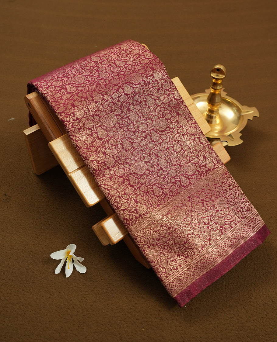 Deep Brown colour semi silk brocade saree featuring intricate Gold Floral kodi patterns across the body, complemented by a rich self colour woven border and pallu, paired with a matching blouse.