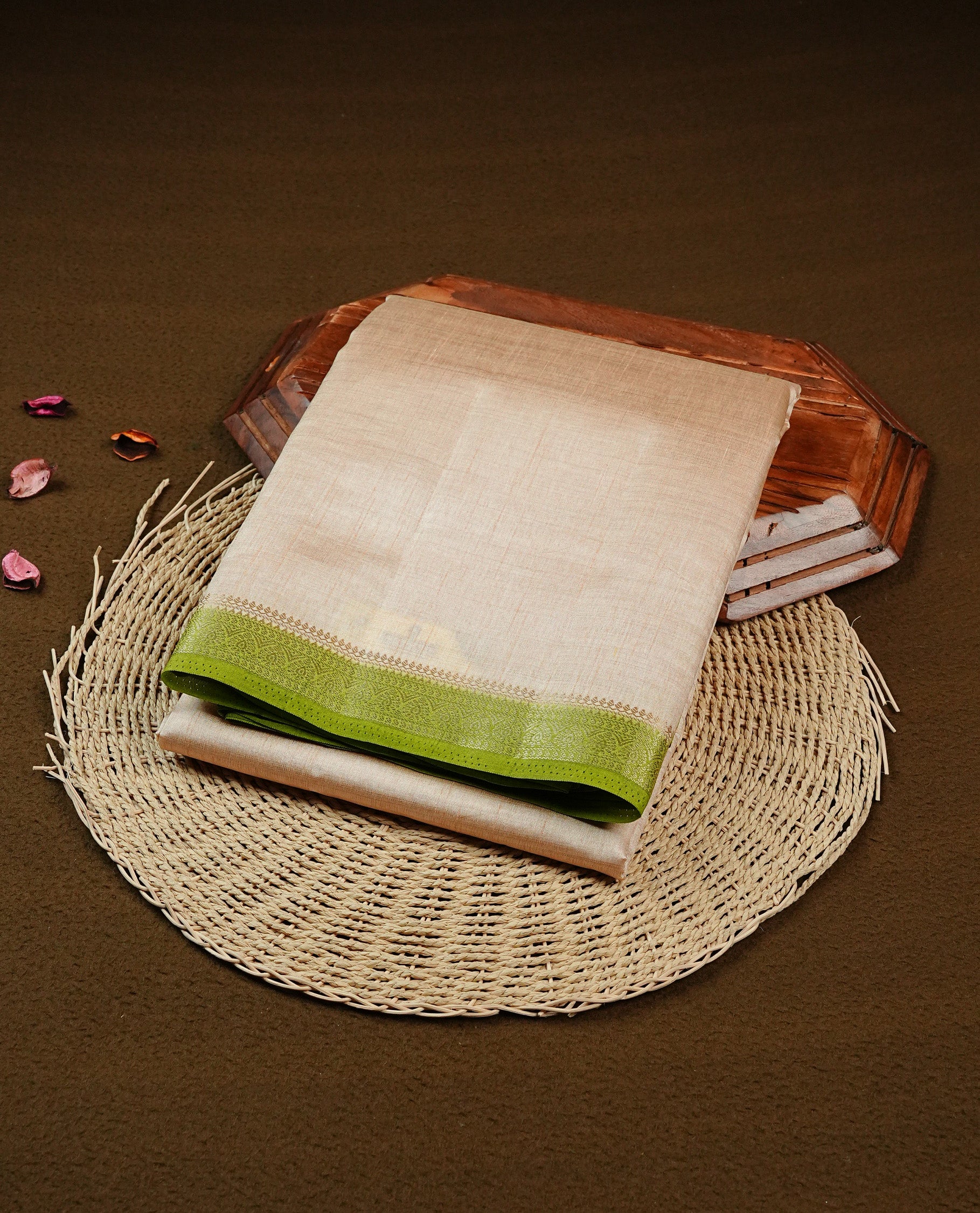 Cream colour Semi Tussar silk saree featuring an elegant plain body, accentuated by a contrast green border adorned with intricate gold zari work, paired with a matching blouse piece.