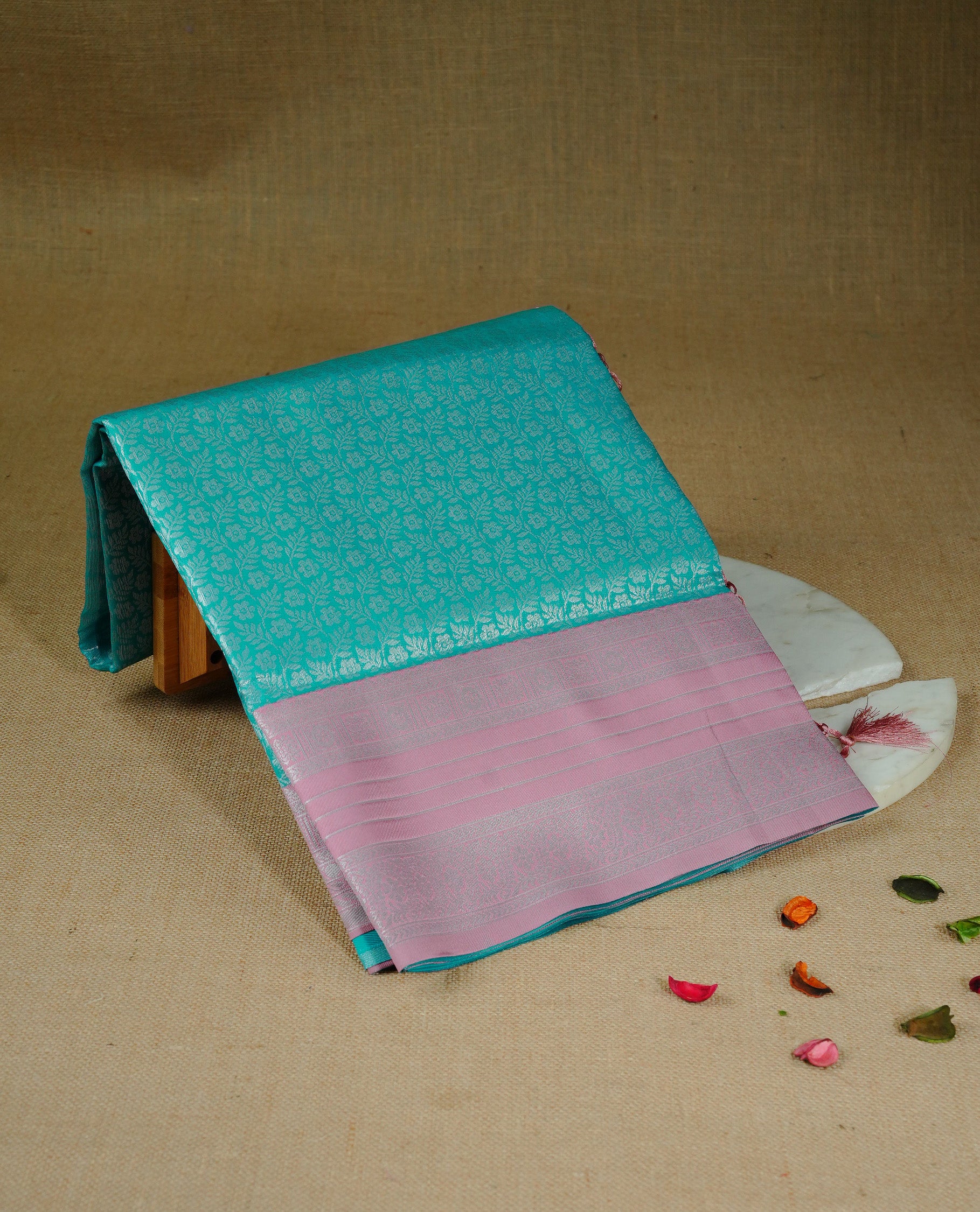 Aqua colour semi silk saree featuring Silver zari Floral pattern on body, complemented by contrast peach colour with silver zari border, comes with matching blouse piece.