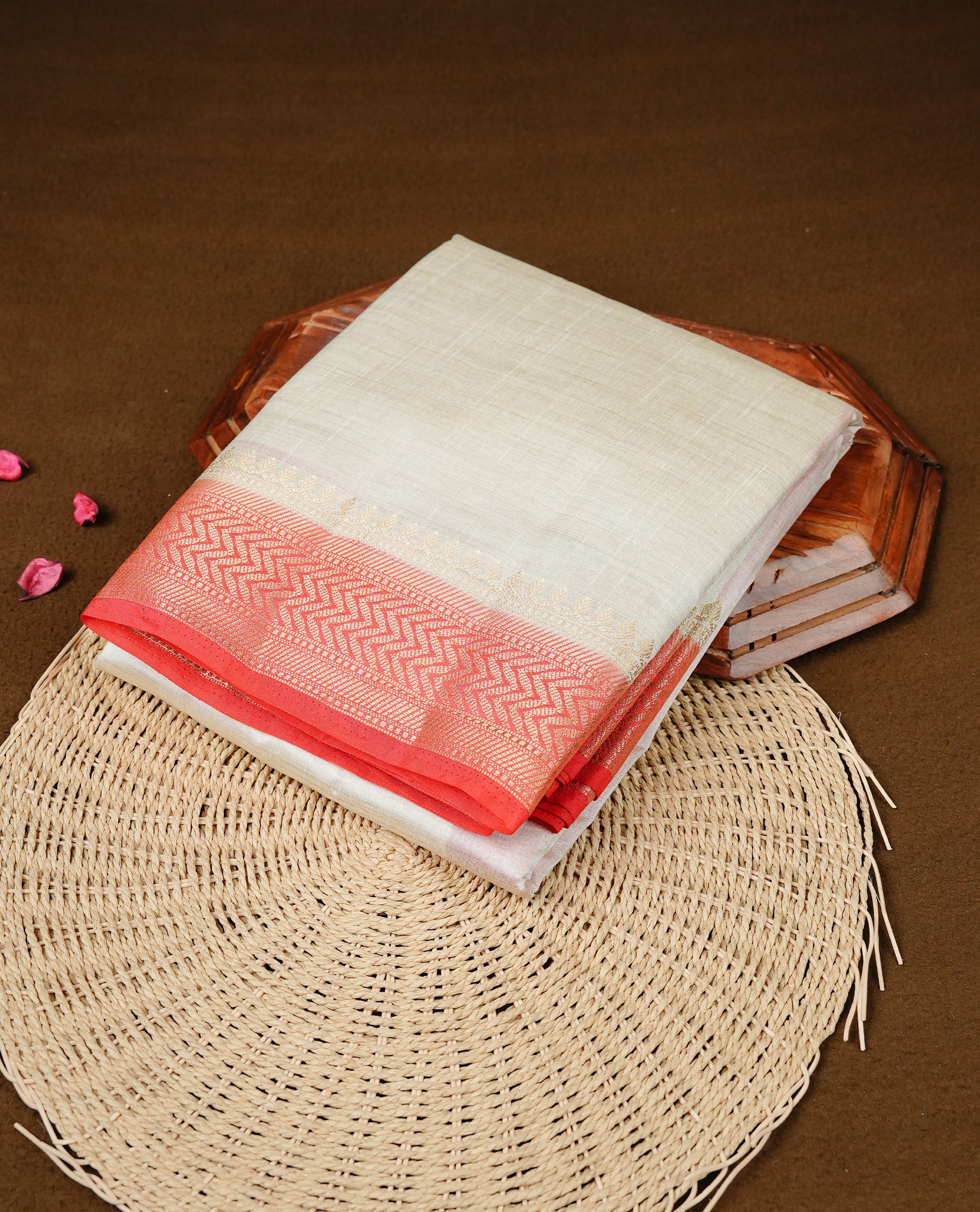 White cream colour Semi Tussar silk saree featuring an elegant plain body, accentuated by a contrast red border adorned with intricate gold zigzag zari work, paired with a matching blouse piece.