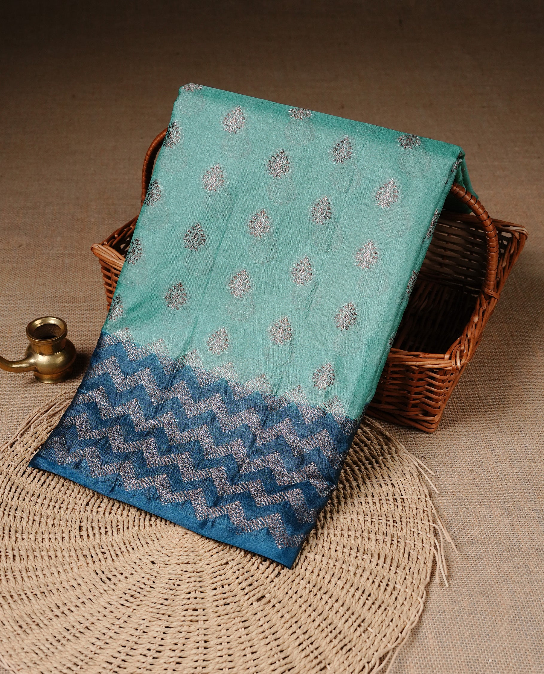 Aqua Colour Tussar silk saree featuring Antique Zari motifs on body, Finished with contrast Teal colour Zigzag zari pattern border, paired with matching blouse piece.