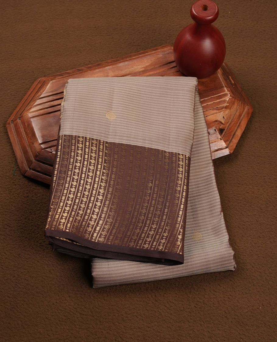 Cream grey colour soft silk saree featuring gold zari motifs on the body, complemented by a contrast chocolate traditional zari border and pallu, paired with matching blouse piece.
