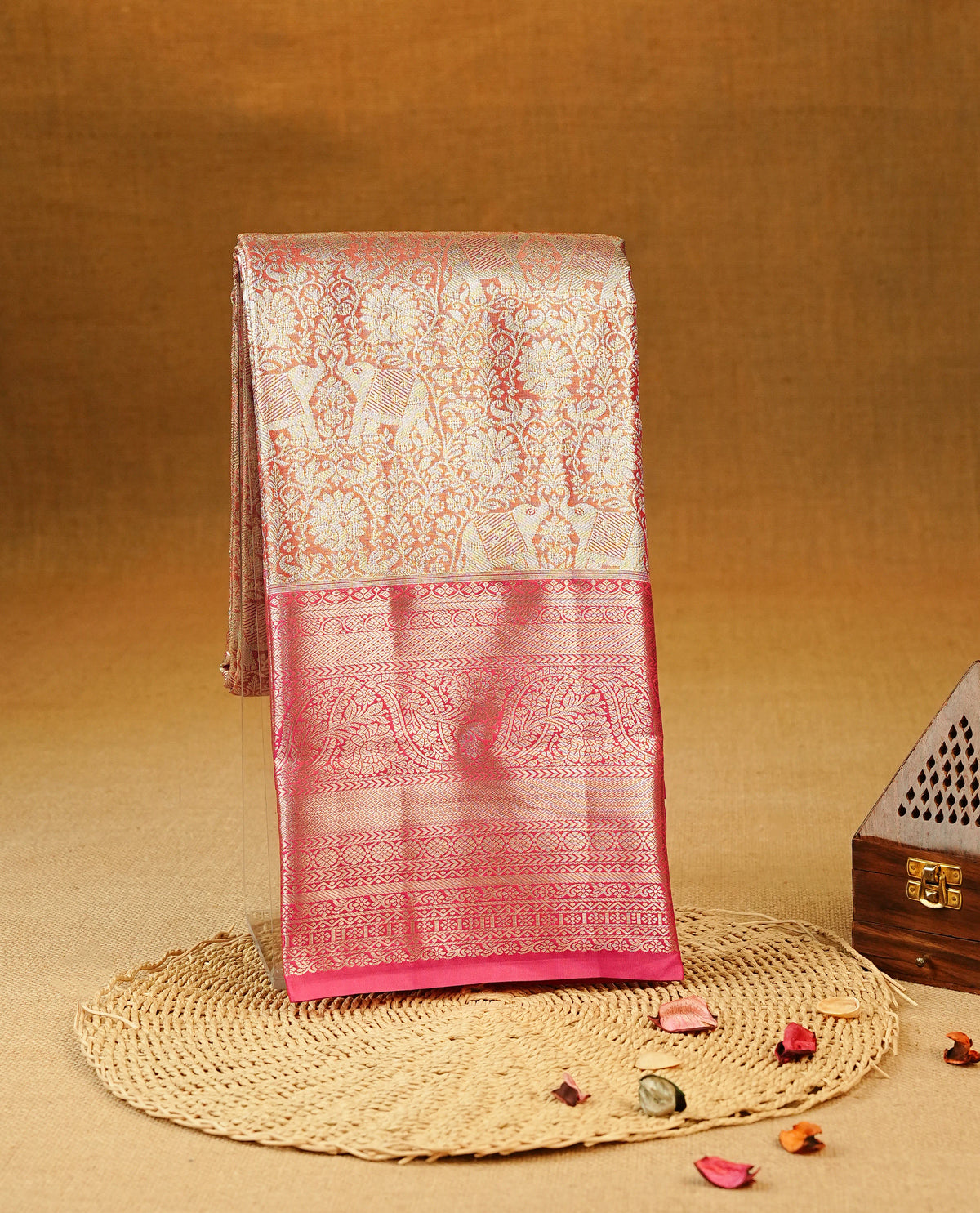 Orange Colour Tissue Silk Saree featuring elephant, peacock, and floral light gold zari woven motifs across the body, a richly woven zari pallu, complemented by a contrast pink border with light gold zari & paired with a matching blouse piece.